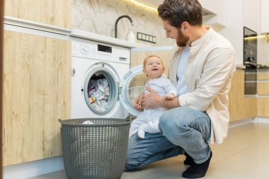 Yıkama hazırlığı. Genç adam ve küçük oğlu çamaşır makinesine koymadan önce elbiselerini ayırıyorlar.