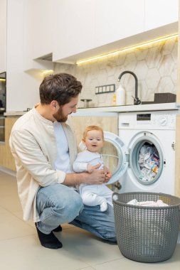 Yıkama hazırlığı. Genç adam ve küçük oğlu çamaşır makinesine koymadan önce elbiselerini ayırıyorlar.