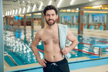 Havuzdaki adam. Yüzme havuzunda havlusu olan kendine güveni tam beyaz bir sporcu.