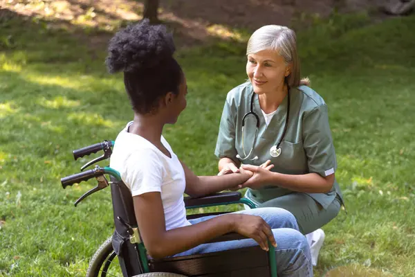 Rehabilitasyon merkezi. Parkta tekerlekli sandalyede bir hemşire ve bir kadın.