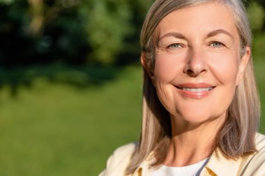 İyi hissediyorum. Kafkasyalı olgun, gülümseyen bir kadın ayakta mutlu bir bakışla duruyor.