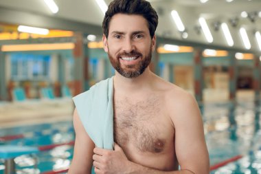 Havuzdaki adam. Yüzme havuzunda havlusu olan kendine güveni tam beyaz bir sporcu.