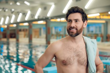 Havuzdaki adam. Yüzme havuzunda havlusu olan kendine güveni tam beyaz bir sporcu.