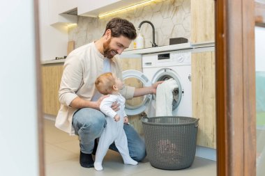 Ev işi. Genç adam ve küçük oğlu çamaşır makinesine koymadan önce elbiselerini ayırıyorlar.