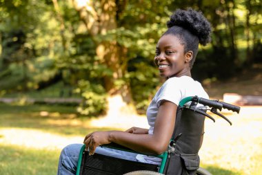 Rehabilitasyon merkezi. Genç esmer kadın tekerlekli sandalyede oturuyor ve gülümsüyor.