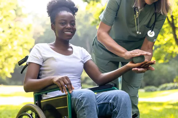 Rehabilitasyon. Parkta Afrikalı Amerikalı bir kadın hastayla rehabilitasyon egzersizleri yapan hemşire.