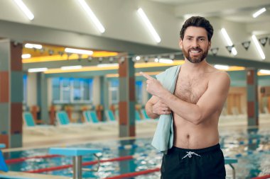 Havuzdaki adam. Yüzme havuzunda havlusu olan kendine güveni tam beyaz bir sporcu.