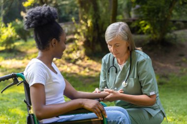 Rehabilitasyon merkezi. Parkta tekerlekli sandalyede bir hemşire ve bir kadın.