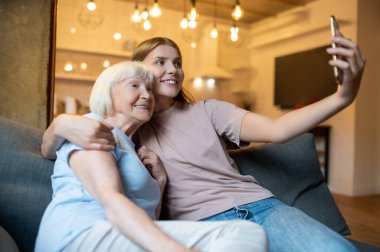 Selfie çekiyoruz. Genç hemşire yaşlı bir kadınla selfie çekiyor ve ikisi de mutlu.