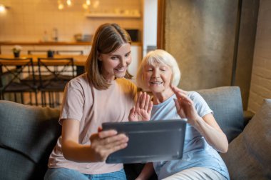Sosyal sorunlar. Yaşlı kadın ve genç gönüllü birlikte dizüstü bilgisayardan bir şey izliyorlar.