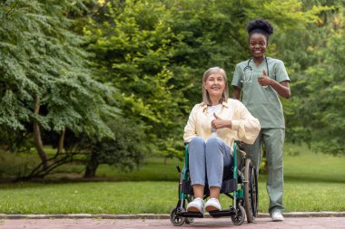 Keyfin yerinde. Tekerlekli sandalyedeki kadın parkta bir hemşireyle yürürken kendini harika hissediyor.