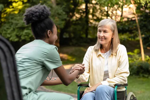 Masaj. Hemşire, kadın bir hastaya masaj topuyla el egzersizi yapmasına yardım ediyor.