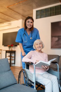 Bakım evi. Yaşlı hastasıyla ilgilenen yardımcım okumayı ve mutlu görünmeyi seviyor.