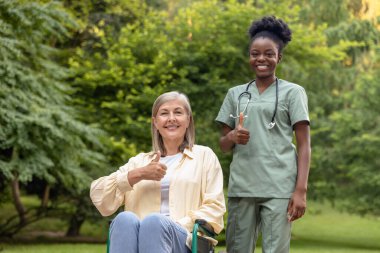 Keyfin yerinde. Tekerlekli sandalyedeki kadın parkta bir hemşireyle yürürken kendini harika hissediyor.