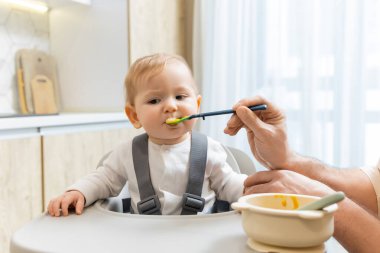 Bebeği besliyorum. Çocuk koltuğunda otururken babası bebeğini besliyor.