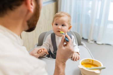 Bebeği besliyorum. Çocuk koltuğunda otururken babası bebeğini besliyor.