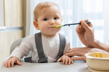 Bebeği besliyorum. Çocuk koltuğunda otururken babası bebeğini besliyor.