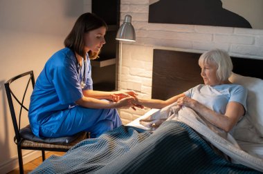 Nabız kontrolü. Doktor yaşlı bir hastanın nabzını kontrol ediyor ve odaklanmış görünüyor.