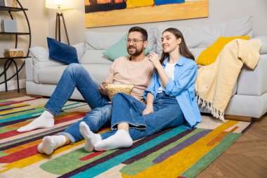 Erkek ve kadın, evde boş vakitlerin tadını çıkarırken yerde birbirlerine sarılıyorlar.