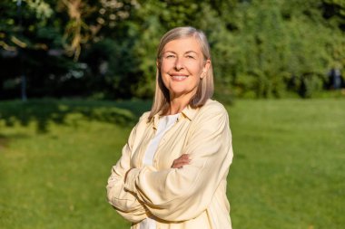 İyi hissediyorum. Kafkasyalı olgun, gülümseyen bir kadın ayakta mutlu bir bakışla duruyor.