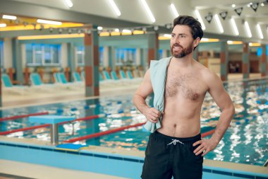 Havuzdaki adam. Yüzme havuzunda havlusu olan kendine güveni tam beyaz bir sporcu.