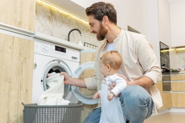 Ev işi. Genç adam ve küçük oğlu çamaşır makinesine koymadan önce elbiselerini ayırıyorlar.