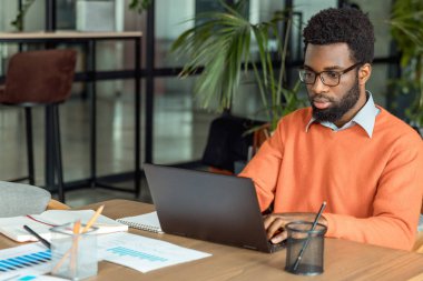 İş adamıyım. Ofiste dizüstü bilgisayarın başında oturan Afrikalı Amerikalı iş adamı.