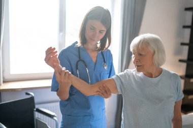 Rehabilitasyon. Rehabilitasyon merkezinde yaşlı bir hastayı muayene eden kadın doktor.
