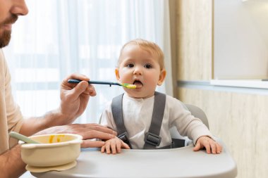 Bebeği besliyorum. Çocuk koltuğunda otururken babası bebeğini besliyor.