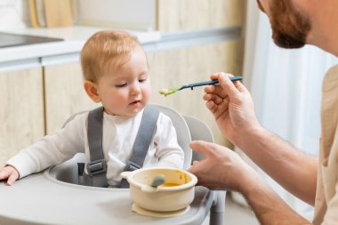 Bebeği besliyorum. Çocuk koltuğunda otururken babası bebeğini besliyor.