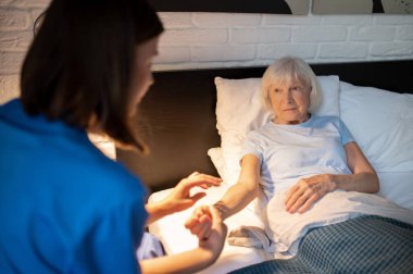 Nabız kontrolü. Doktor yaşlı bir hastanın nabzını kontrol ediyor ve odaklanmış görünüyor.