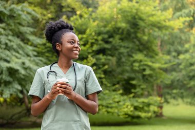 Kahve molası. Afro-Amerikan kahvesini parkta içerken gülümsüyor.