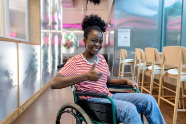 Keyfin yerinde. Tekerlekli sandalyede gülümseyen koyu tenli genç bir kadın.