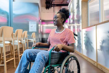 Keyfin yerinde. Tekerlekli sandalyede gülümseyen koyu tenli genç bir kadın.