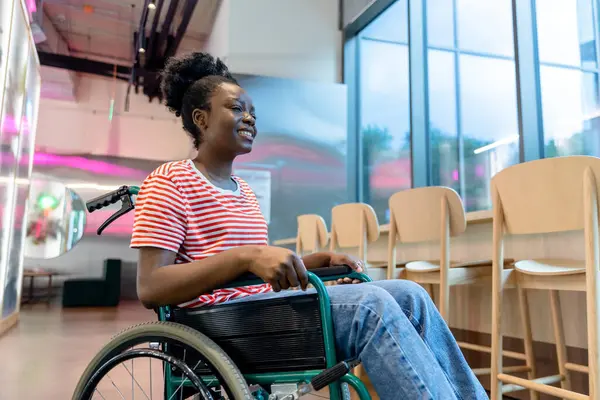 Keyfin yerinde. Tekerlekli sandalyede gülümseyen koyu tenli genç bir kadın.