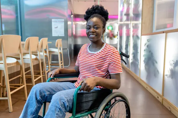 Keyfin yerinde. Tekerlekli sandalyede gülümseyen koyu tenli genç bir kadın.