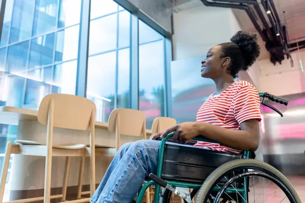 Keyfin yerinde. Tekerlekli sandalyede gülümseyen koyu tenli genç bir kadın.