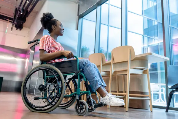 Keyfin yerinde. Tekerlekli sandalyede gülümseyen koyu tenli genç bir kadın.