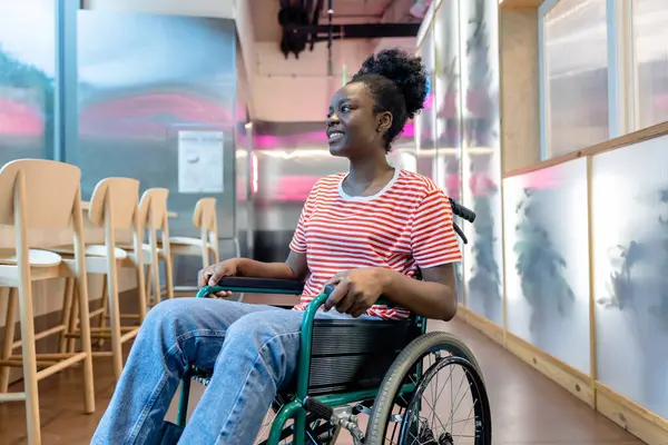 Keyfin yerinde. Tekerlekli sandalyede gülümseyen koyu tenli genç bir kadın.