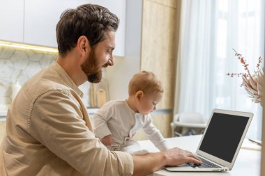 Baba ve oğul. Genç baba ve küçük oğlu evdeki laptopun başında.