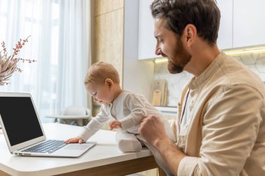 Baba ve oğul. Genç baba ve küçük oğlu evdeki laptopun başında.