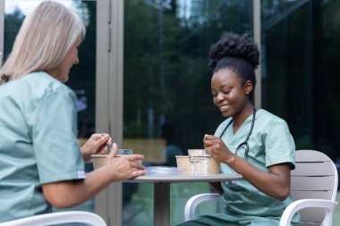 Öğle yemeği vakti. Kadın doktorlar birlikte yemek yiyorlar ve konuşurken olaya dahil oluyorlar.