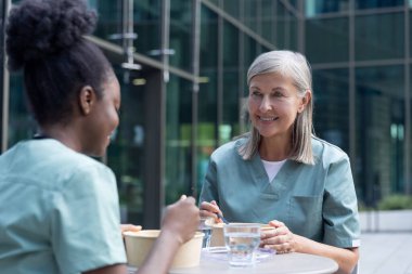 Öğle yemeği vakti. Kadın doktorlar birlikte yemek yiyorlar ve konuşurken olaya dahil oluyorlar.