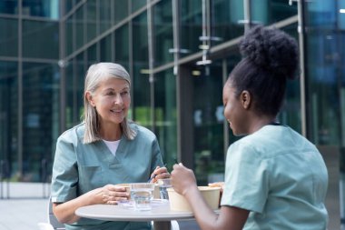 Öğle yemeği vakti. Kadın doktorlar birlikte yemek yiyorlar ve konuşurken olaya dahil oluyorlar.