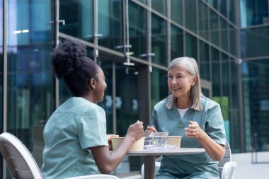 Öğle yemeği vakti. Kadın doktorlar birlikte yemek yiyorlar ve konuşurken olaya dahil oluyorlar.