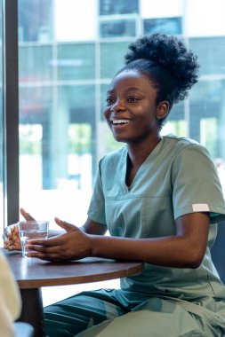 Doktor ve hasta. Afro-Amerikalı bir doktor kadın bir hastayla konuşuyor ve pozitif görünüyor.