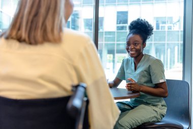 Doktor ve hasta. Afro-Amerikalı bir doktor kadın bir hastayla konuşuyor ve pozitif görünüyor.