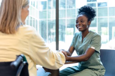 Güven ve destek. Gülümseyen Afrikalı Amerikalı doktor hastasının elini tutuyor ve dost canlısı görünüyor.