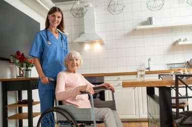 Bakım evi. Bakım asistanı ve hastası mutlu ve gülümsüyor.