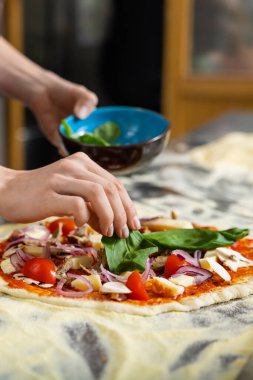 Pizza pişiriyorum. Önlüklü fırıncı pizzacı mutfağında çalışıyor ve pizzanın üstüne sos koyuyor.